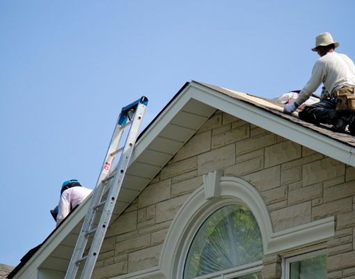 charpentier qui est sur le toit d'une maison en train de travailler