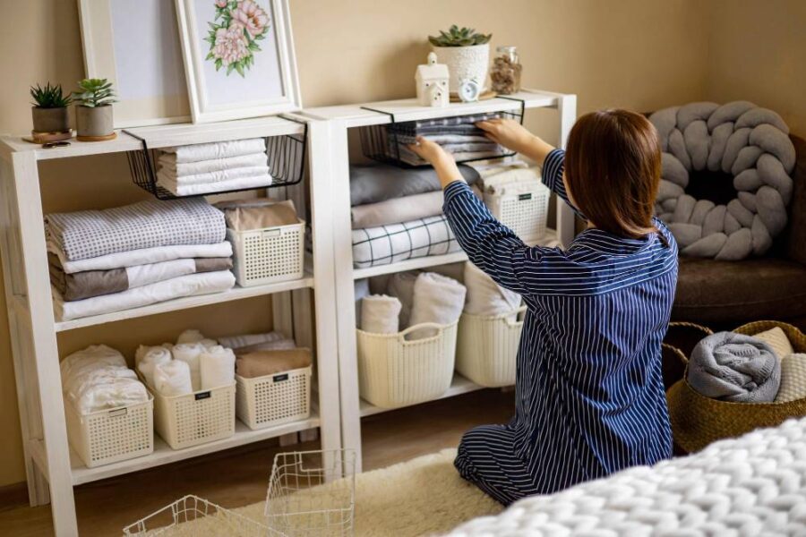 Femme en pyjama rangeant du linge plié dans une armoire