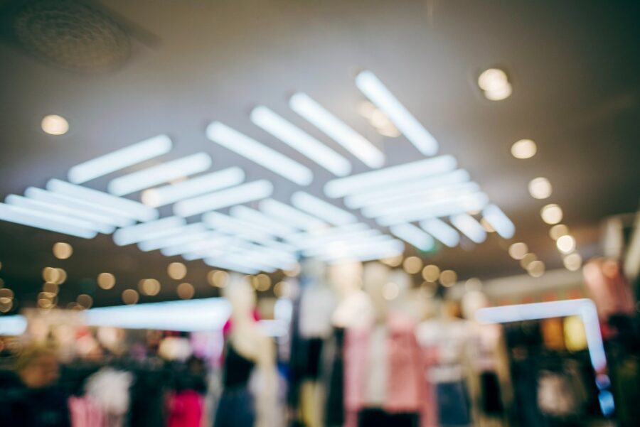 Optimiser l’éclairage intérieur d’un ERP pour dynamiser l’espace INtérieur de magasin flou, avec foule de personnes et néons lumineux au plafond