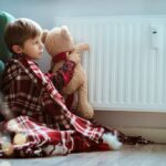 Enfant jouant avec une peluche près d'un radiateur dans sa chambre